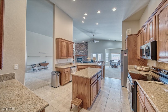 kitchen featuring ceiling fan, stainless steel appliances, light carpet, and a center island