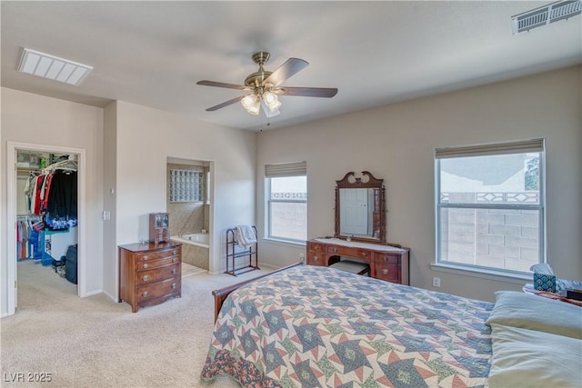 bedroom with a spacious closet, light colored carpet, ceiling fan, and a closet