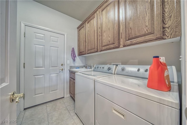 laundry area with light tile patterned flooring, cabinets, sink, and washing machine and clothes dryer