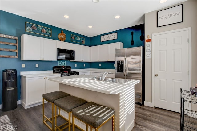 kitchen with an island with sink, gas range, sink, and white cabinetry