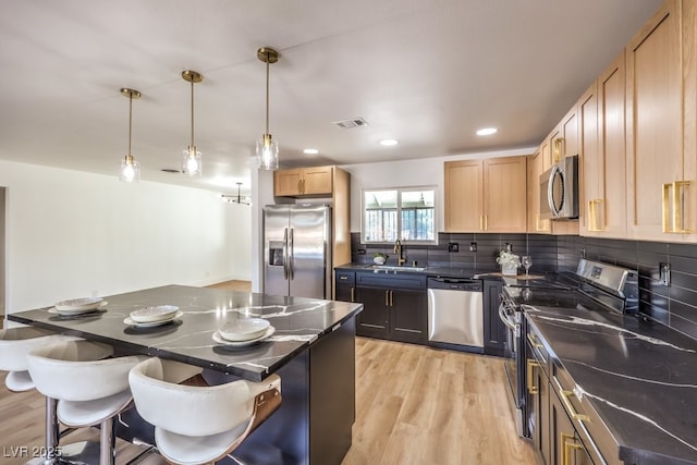 kitchen with sink, light wood-type flooring, decorative light fixtures, stainless steel appliances, and light brown cabinetry