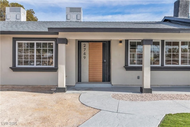 doorway to property with roof with shingles and stucco siding