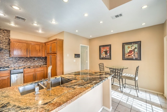 kitchen with sink, stone counters, light tile patterned flooring, and decorative backsplash