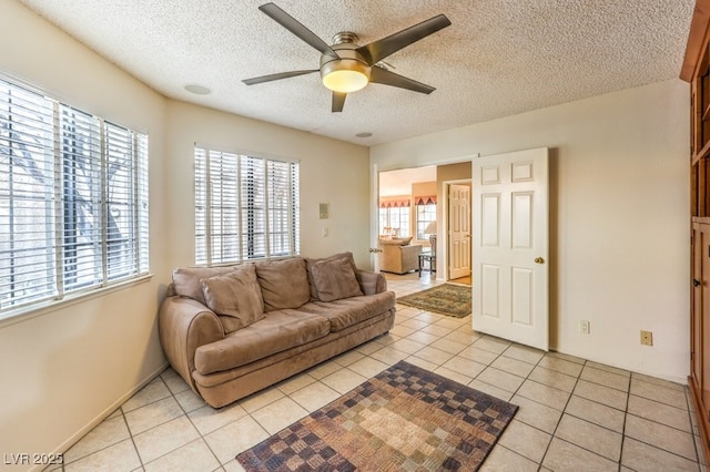 living room featuring light tile patterned floors, ceiling fan, and a textured ceiling