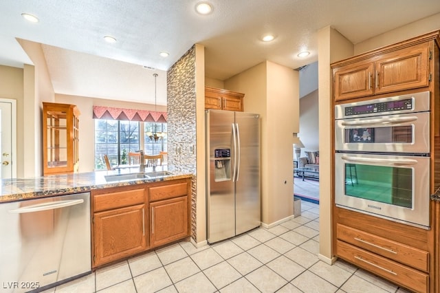 kitchen with light tile patterned floors, stainless steel appliances, a textured ceiling, and light stone counters