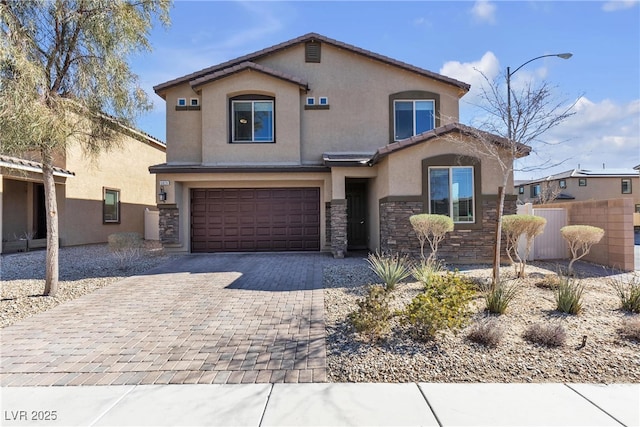 view of front of property featuring stone siding, fence, decorative driveway, and stucco siding