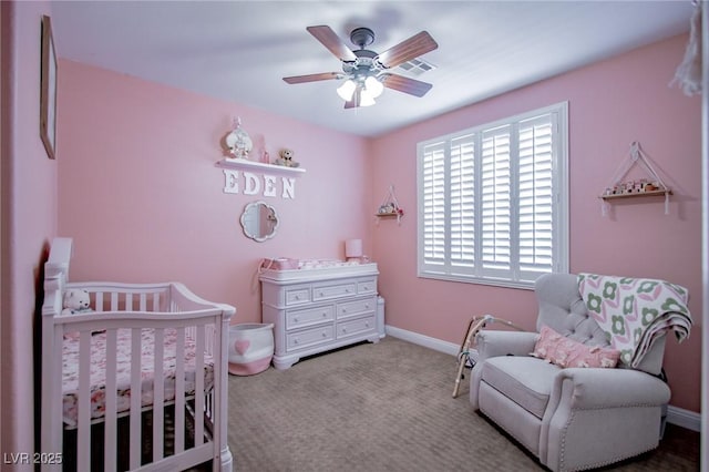 bedroom featuring a crib, ceiling fan, and light colored carpet