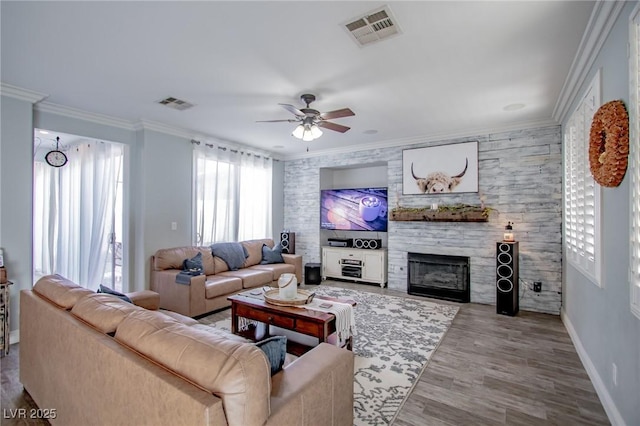 living room with a fireplace, hardwood / wood-style flooring, crown molding, and ceiling fan