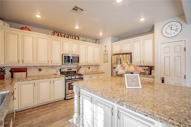 kitchen with light stone countertops, cream cabinets, and stainless steel appliances