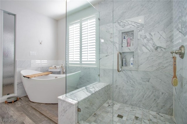 bathroom featuring plus walk in shower, wood-type flooring, and tile walls