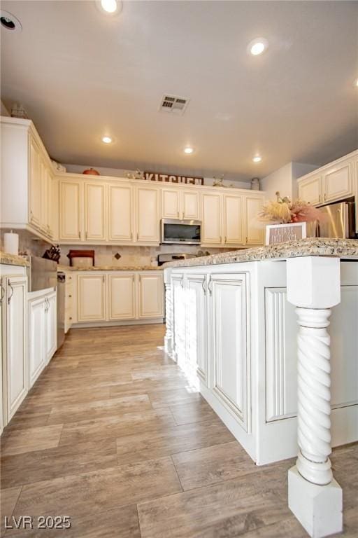 kitchen featuring light stone counters, stainless steel appliances, and light hardwood / wood-style flooring