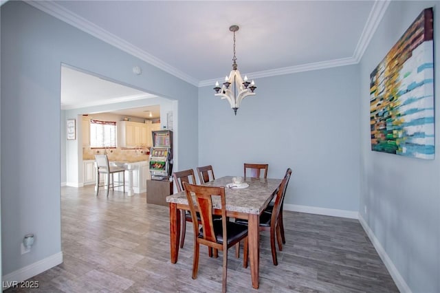 dining area with ornamental molding, a chandelier, and wood-type flooring