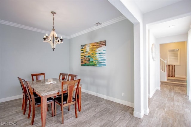 dining space with light hardwood / wood-style flooring, ornamental molding, and a notable chandelier