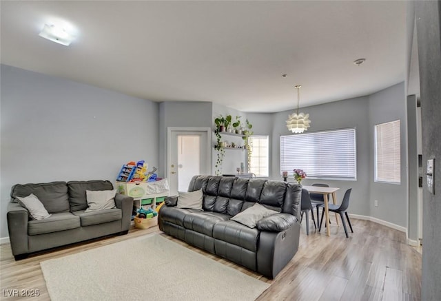 living room with light wood-type flooring and a notable chandelier