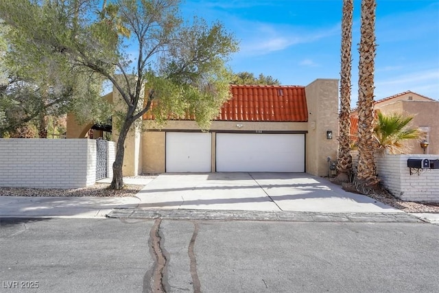 view of front facade with concrete driveway, a tiled roof, an attached garage, and stucco siding