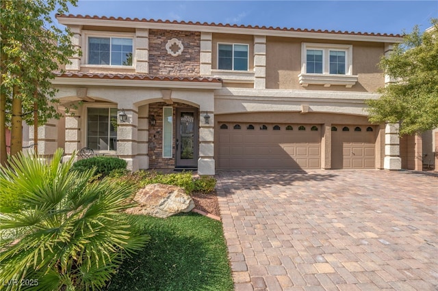 view of front facade featuring a tiled roof, stucco siding, decorative driveway, and a garage