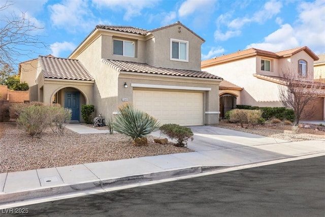 mediterranean / spanish-style house featuring concrete driveway, stucco siding, a tile roof, and an attached garage