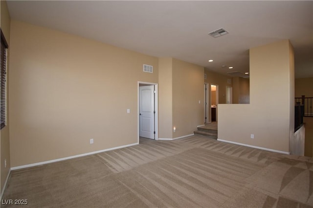 empty room with baseboards, visible vents, and light carpet