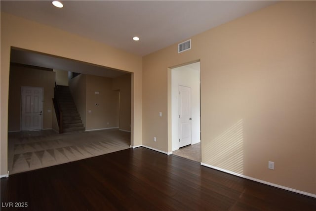 unfurnished room with recessed lighting, wood finished floors, visible vents, baseboards, and stairs