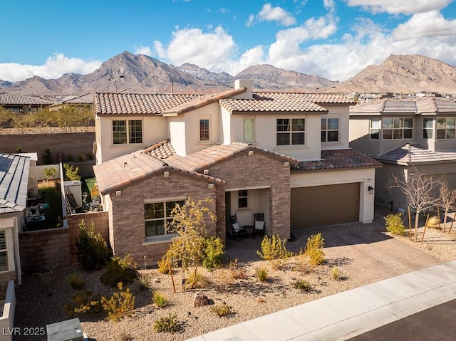 view of front of home with stucco siding, an attached garage, a mountain view, a tiled roof, and decorative driveway