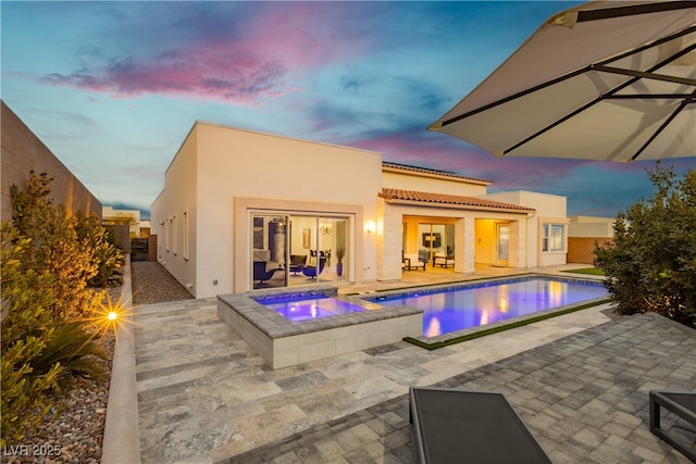 exterior space featuring a tile roof, stucco siding, a patio area, an in ground hot tub, and an outdoor pool