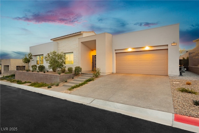 view of front facade with a garage, driveway, and stucco siding