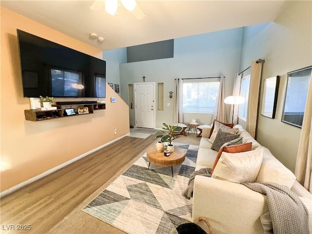 living room featuring ceiling fan, light wood finished floors, and baseboards