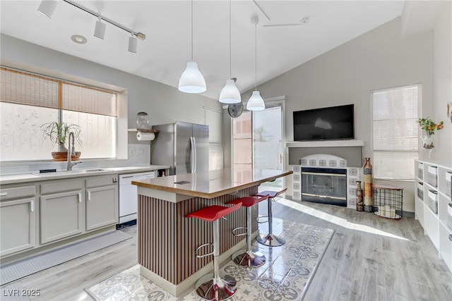 kitchen featuring white dishwasher, light countertops, freestanding refrigerator, a center island, and pendant lighting