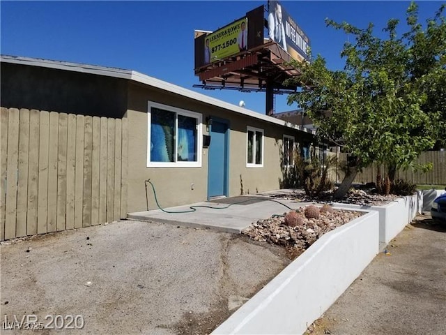 view of front of property with fence, a patio, and stucco siding