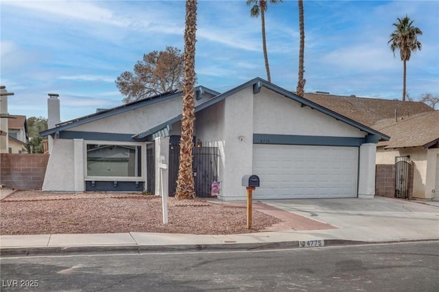 mid-century home with a garage, driveway, fence, and stucco siding