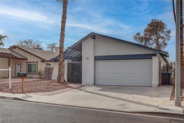 view of front of property featuring concrete driveway, fence, an attached garage, and stucco siding