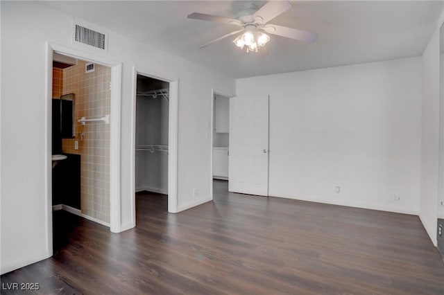 unfurnished bedroom with visible vents, a ceiling fan, dark wood-style flooring, a walk in closet, and a closet