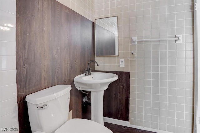 half bathroom with toilet and tile walls