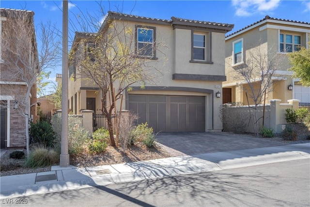 view of front facade with decorative driveway, an attached garage, fence, and stucco siding