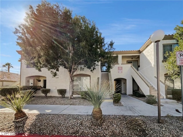 view of front of home with a tile roof, stairway, and stucco siding