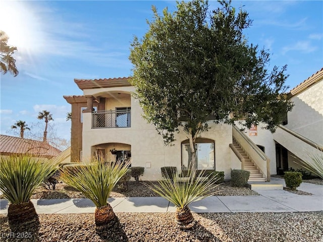 view of front of property with stairs, a balcony, and stucco siding