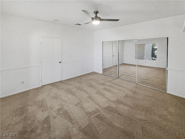 unfurnished bedroom featuring a closet, carpet, visible vents, and a ceiling fan