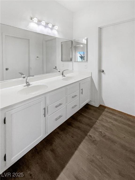 bathroom with double vanity, wood finished floors, and a sink