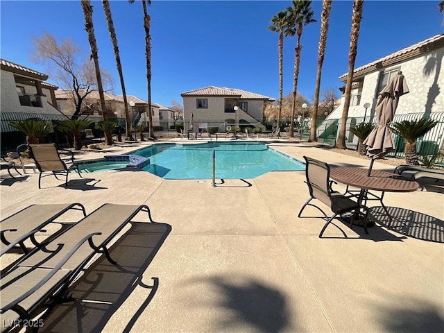 view of pool with a residential view, a pool with connected hot tub, a patio area, and fence