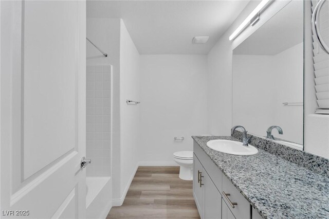 full bath featuring baseboards, toilet, vanity, wood finished floors, and shower / bathtub combination