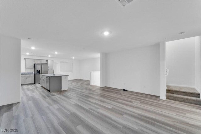 unfurnished living room with light wood finished floors, visible vents, a sink, and recessed lighting