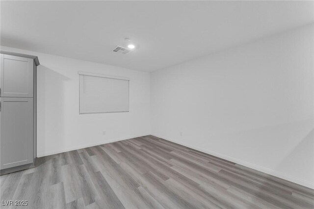 unfurnished room with baseboards, visible vents, and light wood finished floors