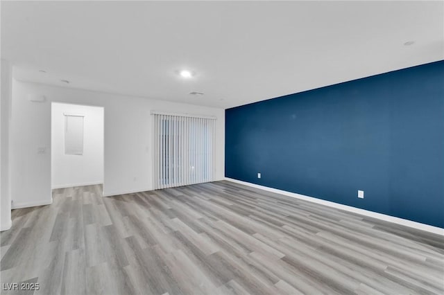 empty room featuring light wood-style floors, visible vents, and baseboards