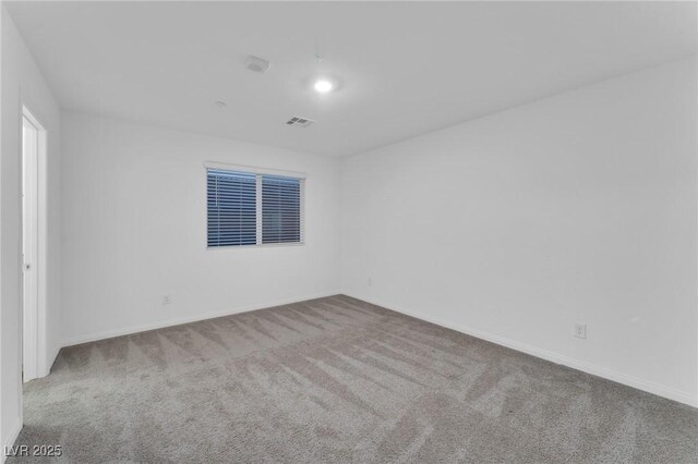 spare room featuring light carpet, visible vents, and baseboards