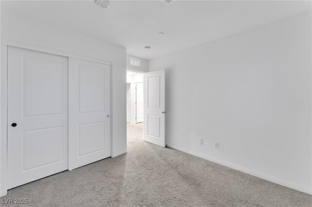 unfurnished bedroom featuring baseboards, a closet, and light colored carpet