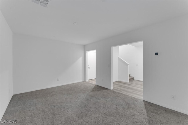 interior space with light carpet, baseboards, stairs, and visible vents