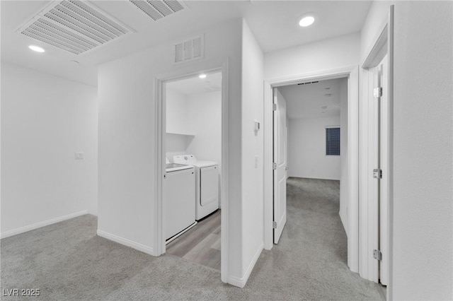 hallway with light carpet, independent washer and dryer, and visible vents