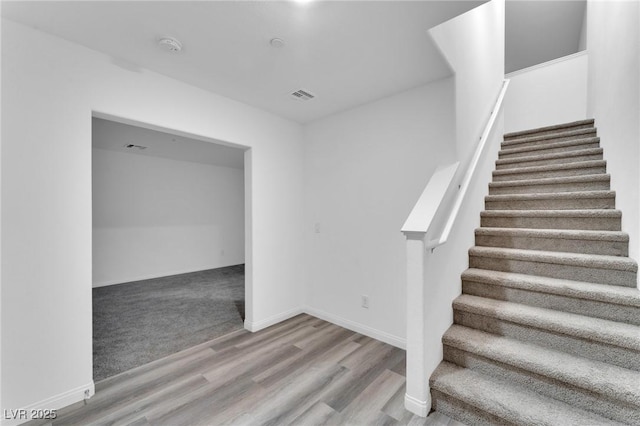 stairway featuring visible vents, baseboards, and wood finished floors