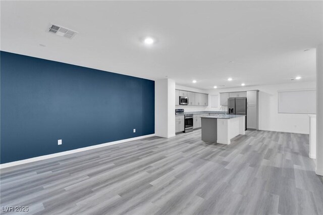 kitchen featuring open floor plan, stainless steel appliances, light countertops, and visible vents