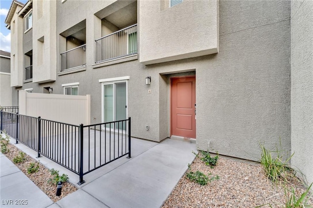 doorway to property with fence and stucco siding